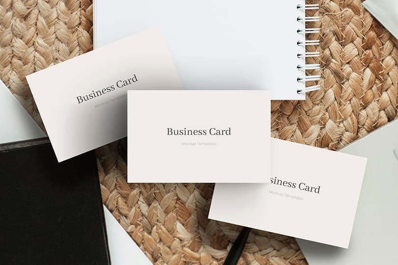 Three Business Card Mockup With Notebook and Rattan Background